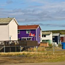 Row of houses with Canadian flag waving in the town of Inuvik Northwest Territories in Canada. Housing rights